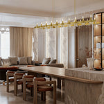 Brass-finish clear glass tube linear chandelier in a furnished room