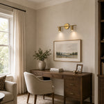 Brass twin-cylinder picture light illuminating artwork in an office
