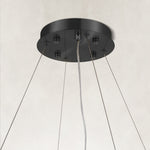 Black canopy and suspension cables of a layered ring chandelier.