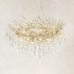Brass branch ring chandelier with hanging clear crystal pendants against a warm textured background