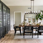 Black cylinder linear chandelier above a dining table with a pumpkin display.