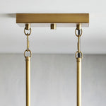 Brass-tone ceiling canopy and rod attachments of the linear chandelier.