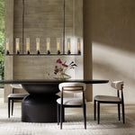 Cylinder linear chandelier above a dark dining table in a furnished interior.