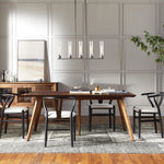 Cylinder linear chandelier above a dining table against a paneled wall.
