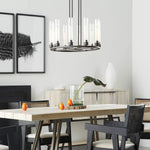 Black cylinder ring chandelier above a light wooden dining table.