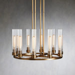 Brass-tone ring chandelier with upright clear glass cylinders against a gray wall.