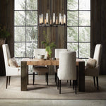 Cylinder ring chandelier above a dining table beside tall windows.