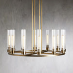 Wide brass-tone cylinder ring chandelier against a gray wall.