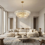 Clear round chandelier above a cream sofa and round coffee table.
