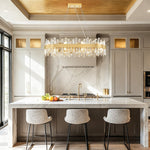 Gold-tone crystal ribbon oval chandelier above a kitchen island with a gold ceiling recess.