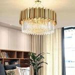 Gold-tone crystal drum chandelier beside a window and a bookcase.