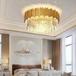 Illuminated crystal flush mount above a bed in a furnished bedroom.