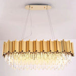 Illuminated oval crystal chandelier hanging from a gold-tone canopy.