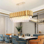Oval crystal chandelier above a long table with blue and orange dining chairs.