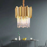 Single illuminated crystal crown pendant above a table against a dark wall.