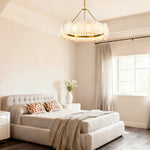 Gold-tone ring chandelier in a bright bedroom with a tufted bed.
