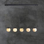 Five alabaster globes arranged along a black linear frame against a gray wall.