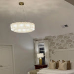 Gold-hardware layered alabaster ring chandelier in a bedroom.