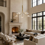 Gold-tone leaf glass chandelier near a fireplace in an interior setting