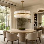 Glass drum chandelier above a round dining table beside an arched doorway.