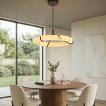 Illuminated alabaster ring pendant with black supports above a round dining table