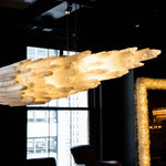 Layered stone pendant seen from below beside a window in a furnished interior.