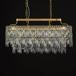 Gold-tone oval crystal chandelier, unlit fixture against dark background.