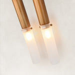 Illuminated frosted tubes and bronze-tone holders on a wall sconce.