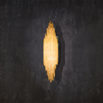 Illuminated vertical selenite wall sconce against a dark wall.