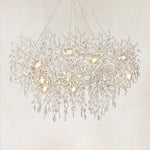 Silver branch ring chandelier with hanging clear crystal pendants against a warm textured background