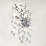 Silver branch wall sconce with clear crystal pendants on a warm textured wall