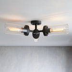 Black flush mount with three horizontal clear glass cylinders on a ceiling.