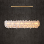 Illuminated linear selenite chandelier with a rectangular canopy against a dark wall.