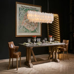 Long selenite chandelier hanging above a wooden dining table.