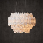 Illuminated round selenite chandelier with a staggered lower edge.