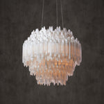 Round chandelier with overlapping pointed selenite pieces against a dark background.