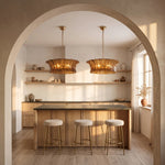 Two smoke ribbed-glass drum chandeliers above a wood kitchen island beneath an arch