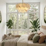 Two-tier alabaster disc chandelier above a bed beside large windows