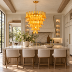 Tiered amber chandelier above a kitchen island in a bright neutral interior.