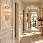 Tiered glass wall sconces with gold-tone hardware along a light-colored hallway.