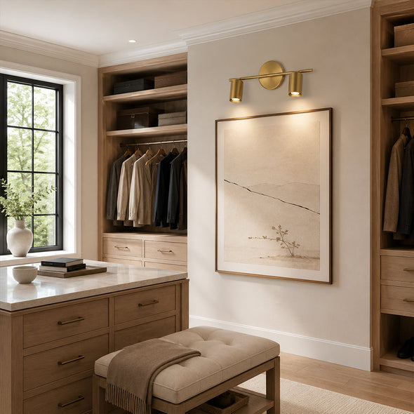 Brass twin-cylinder picture light illuminating framed artwork in a dressing area