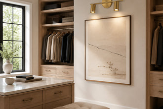 Brass twin-cylinder picture light illuminating framed artwork in a dressing area