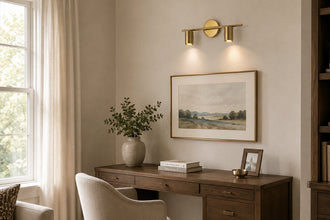 Brass twin-cylinder picture light illuminating framed artwork above a home office desk