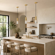 Three brass and clear glass pendant lights above a marble kitchen island