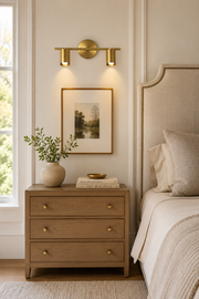 Twin-head brass wall sconce above a bedside table in a warm neutral bedroom