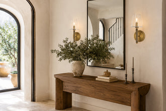 Two aged brass wall sconces flanking a mirror above an entryway console