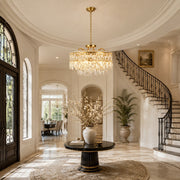 Illuminated crystal drum chandelier in a bright foyer with a curved staircase