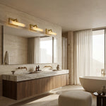 Brass-tone picture lights above a broad mirror seen from the side of the vanity.