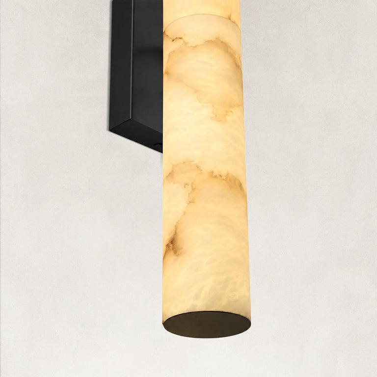 Illuminated alabaster panel and black wall-sconce backplate.