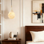 Alabaster teardrop pendant beside a bed.